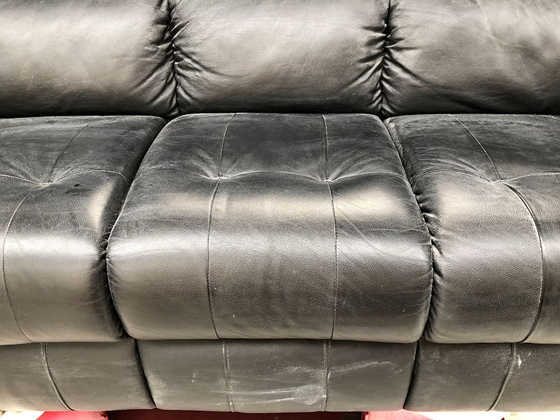 Black leather couch with plaster dust
